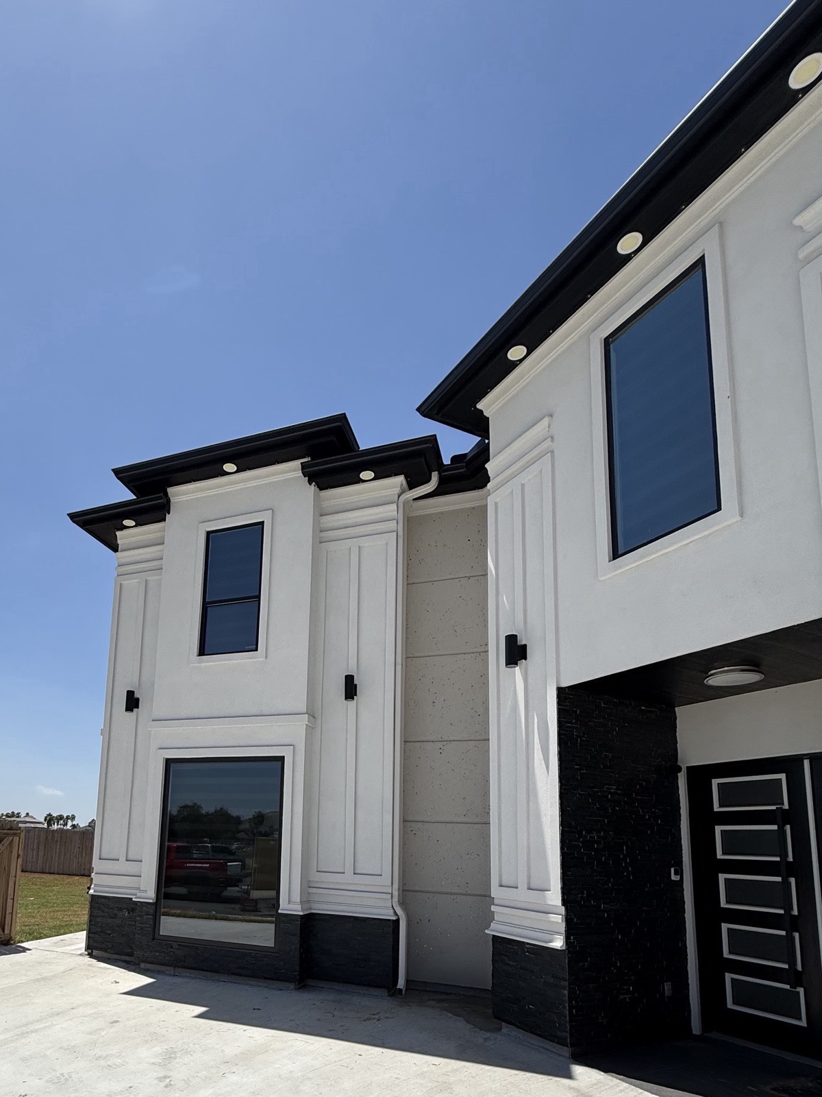 Front elevation of a white stucco home with black seamless gutters along the rooflines