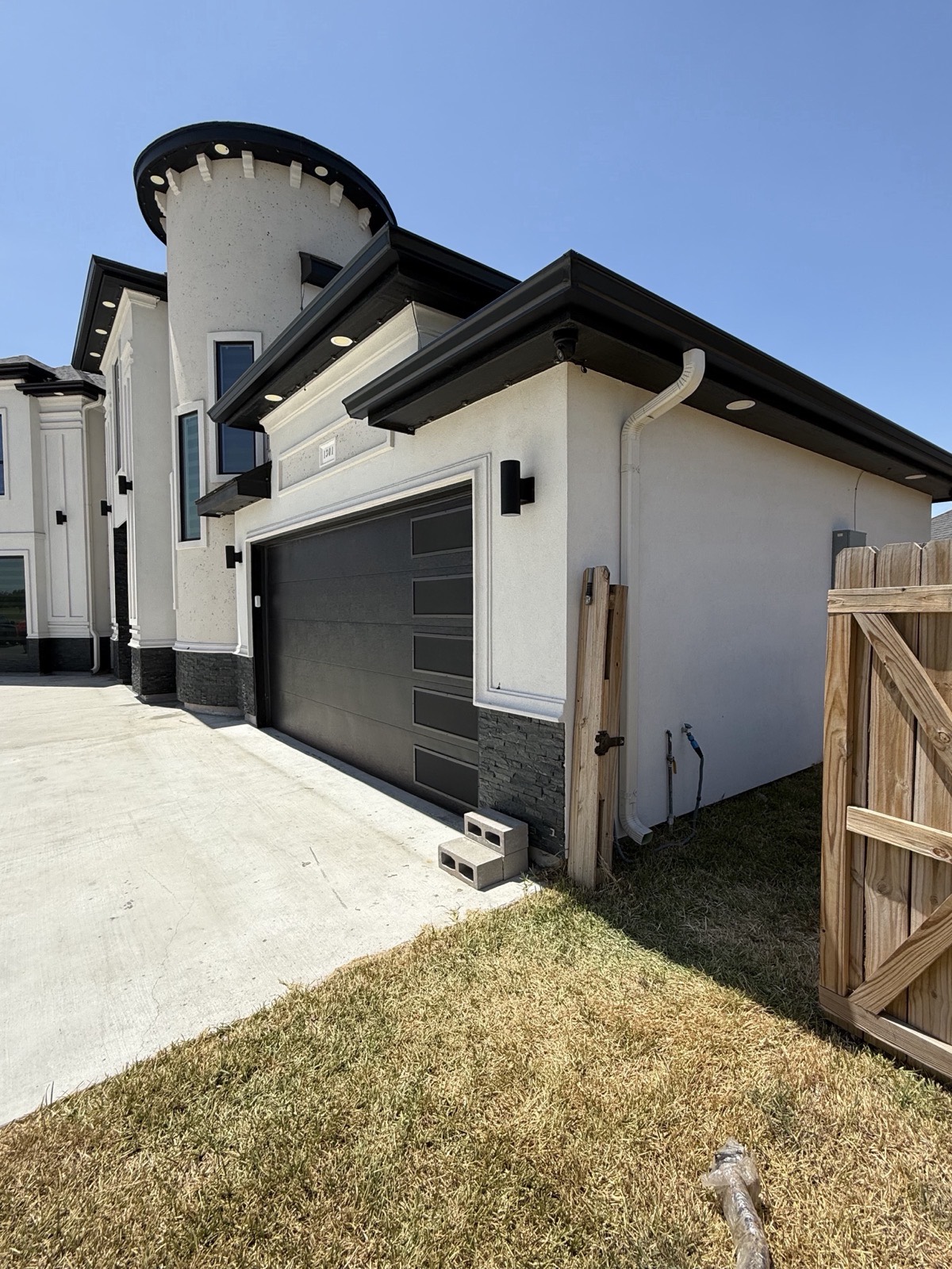Seamless gutter and downspout running down the garage side of a white stucco home